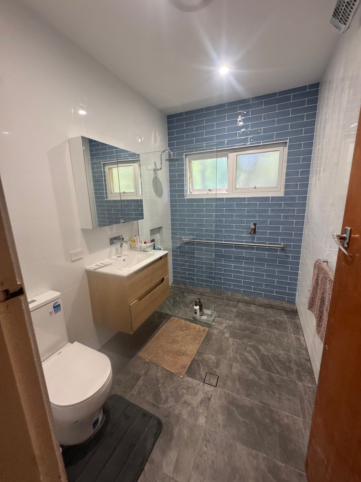 Blue subway tile walk-in shower with timber vanity