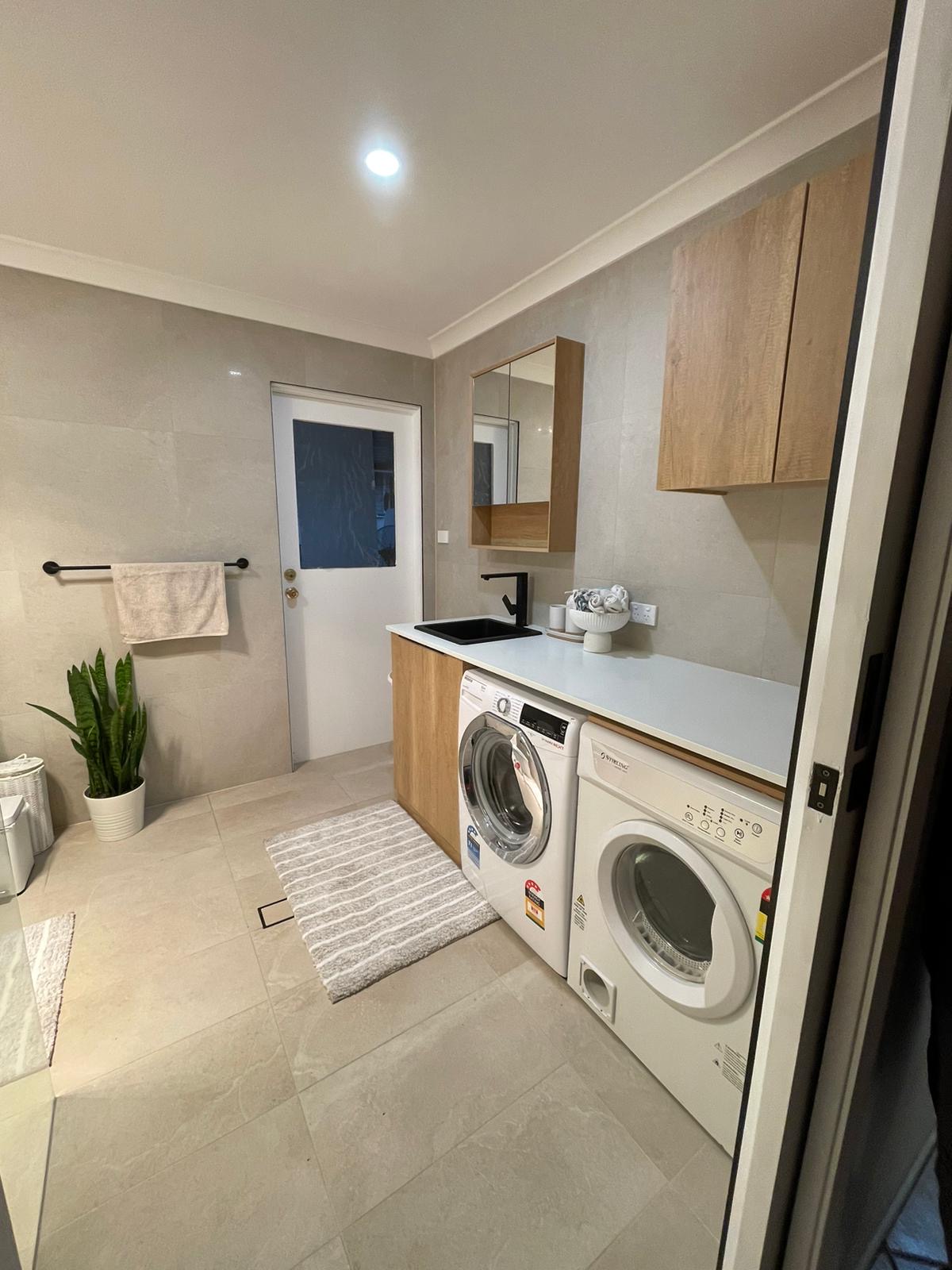 Modern laundry with stone-look tiles and timber cabinetry