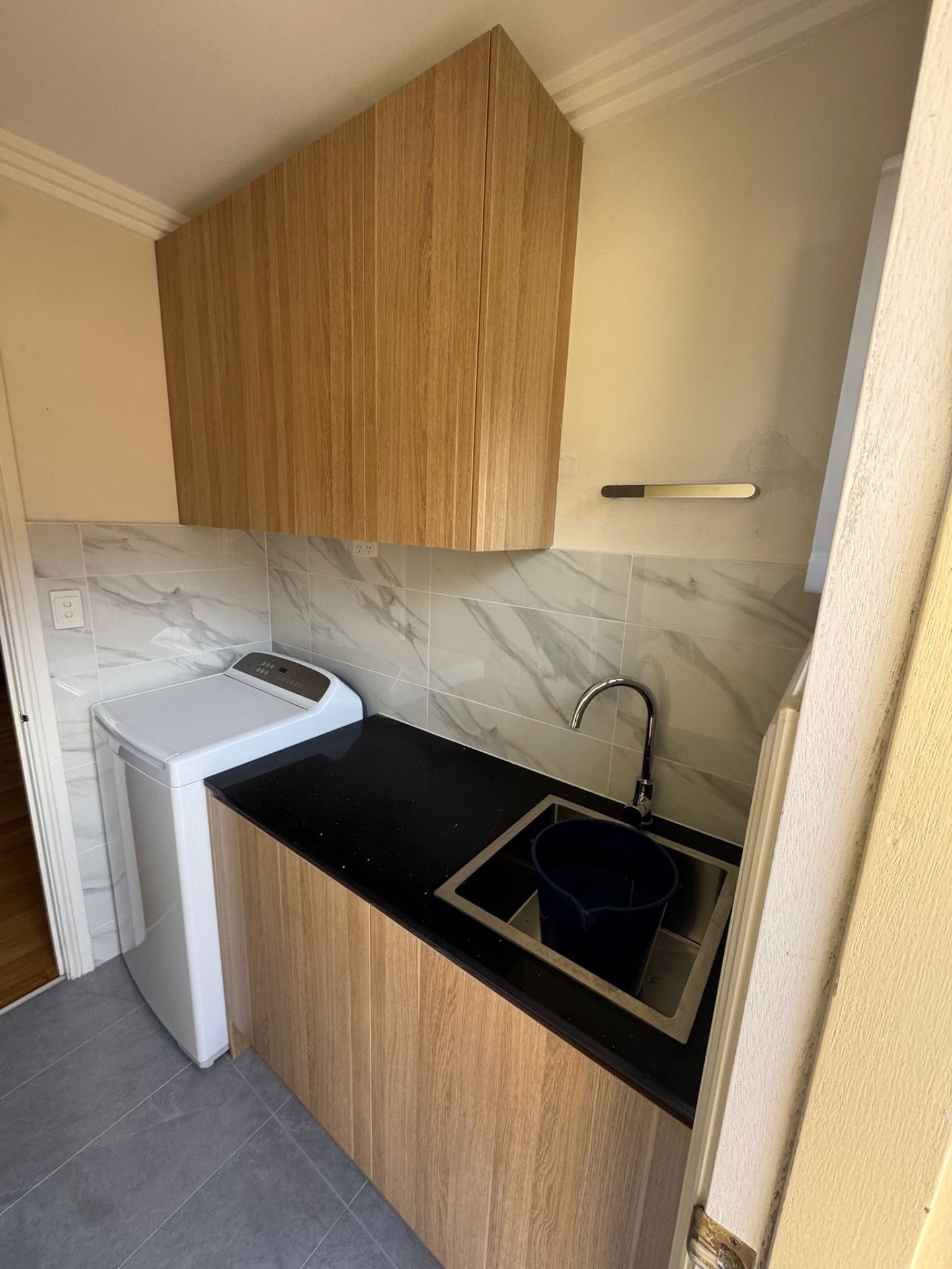 Compact laundry with marble splashback and black stone benchtop